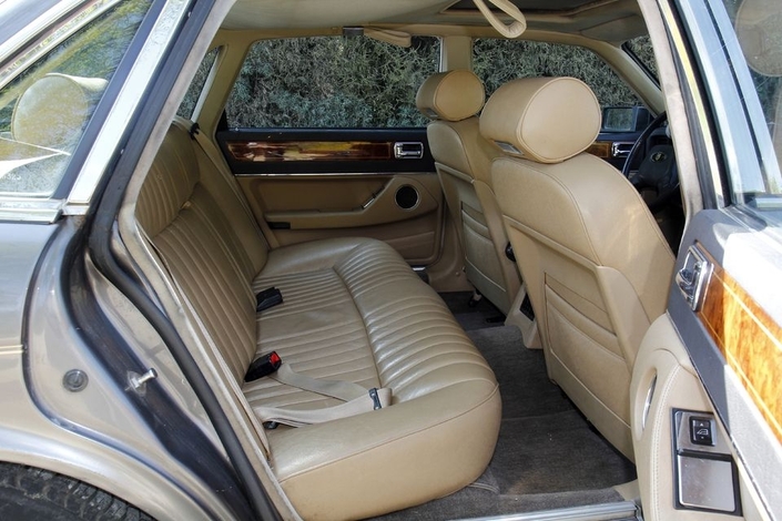 Le compartiment arrière d'une XJ40 Sovereign donne envie, avec son alléchante banquette en cuir. Cela dit, sur cet exemplaire un peu âgé, on voit le ciel de toit s'avachir...