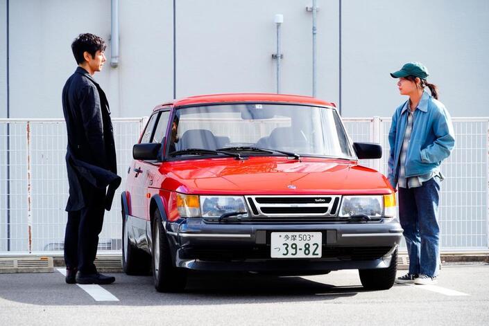 Yusuke à gauche et Misaki à droite encadrent la Saab 900.