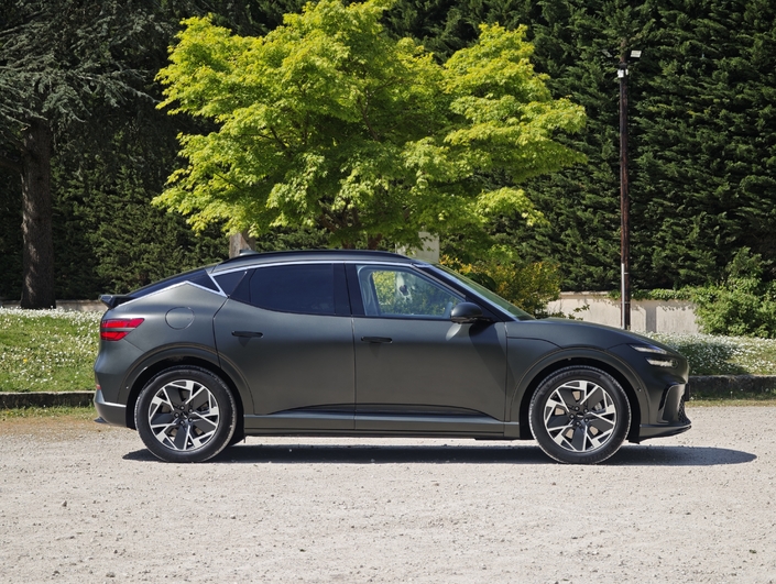 Le GV60 mesure 4,55 m de long, comme ses concurrents (à quelques cm près). Il présente une vraie ligne de SUV coupé, avec un jonc chromé supérieur au décroché original sur le montant arrière.