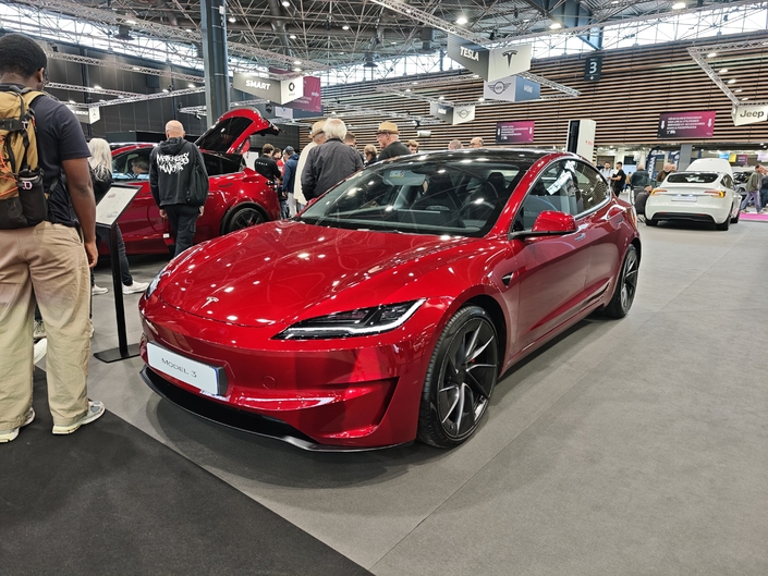 La Model 3 Performance, ici dans son joli rouge "Ultra", coûte 57 490 €. On trouve sur le stand une version blanche plus bas de gamme (en arrière-plan de la photo).