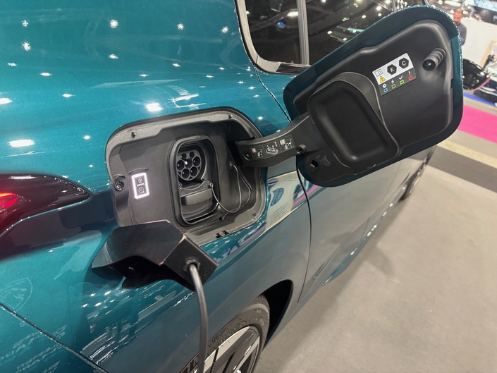 Peugeot expose une e-308 sur son stand au salon de Lyon, mais ne dispose pas de fausse borne permettant de mimer une voiture en charge. A la place il a simplement installé une pièce en métal aimantée sur la carrosserie, juste à côte de la trappe abritant la prise de recharge. 