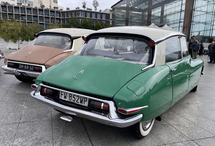 Au premier plan, une Citroën DS d'avant 1958, comportant les ailes courtes et l'échappement central "queue de carpe". Derrière, une ID19 à peine plus récente. Les coloris flashys sont stupéfiants !